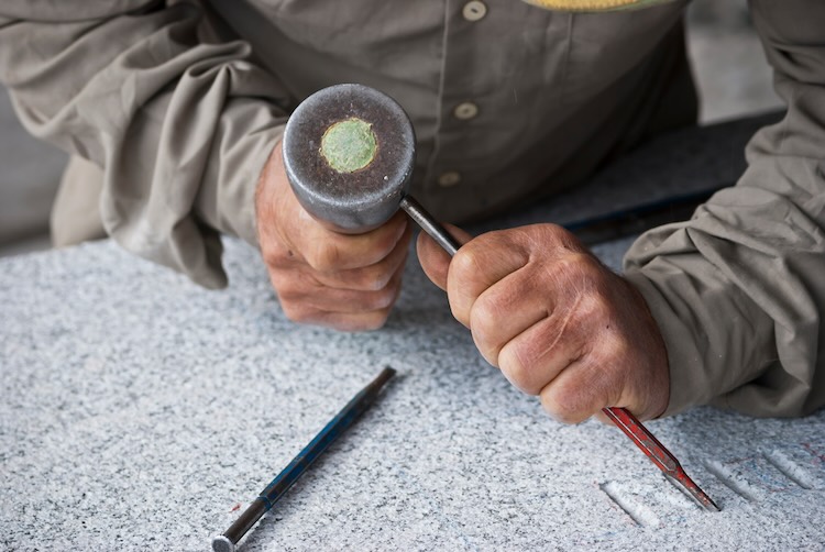 stonemason Stone mason doing some letters on a granite stone